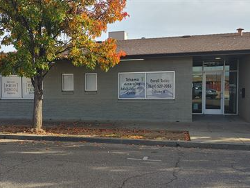 the front of the adult education building, painted grey, with new window art containing the name of the school & the logo.
